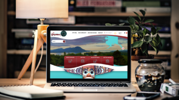 Laptop on a wooden desk displaying the Saxman, AK website homepage